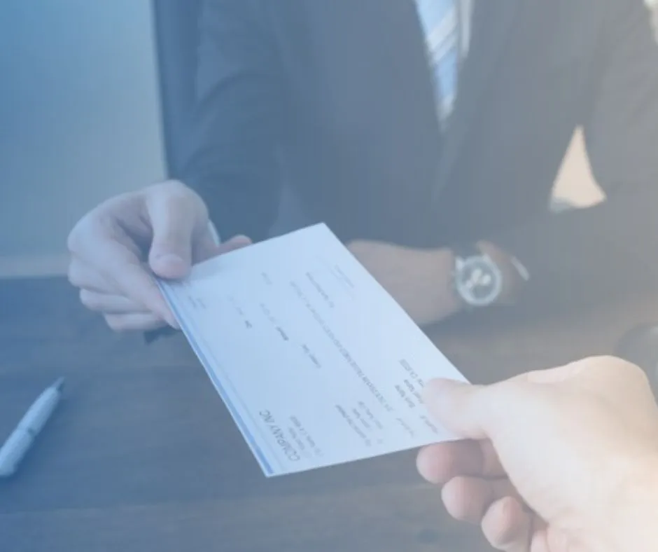 A paycheck being handed across a desk