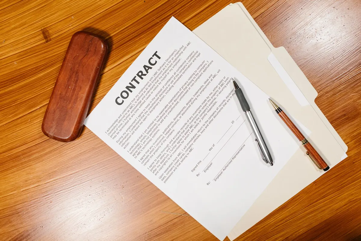 Employment contract with an arbitration clause and pens on a wooden desk