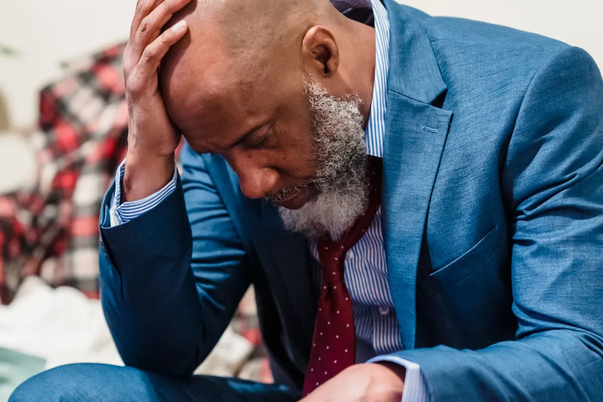 Stressed employee in a suit sitting with his head in his hand